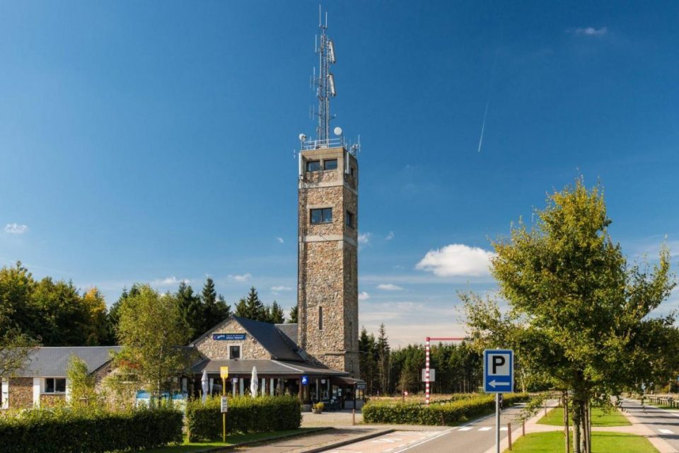 La tour d’observation en pierre du Signal de Botrange et le bâtiment d’accueil, sous un ciel bleu.